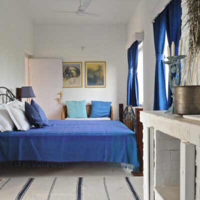 Cozy bedroom with blue bedspread, matching curtains, and white walls creating a calm, minimalist interior design look