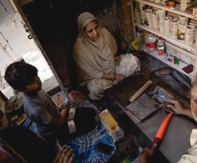 A worker carefully shaping an bangle, heating it for finishing in his crafting space.