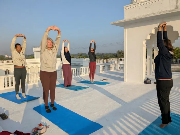 People doing yoga on rooftop with an Yoga Instructor