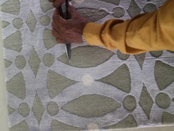 6 Artisan carving geometric design into textured surface, possibly artwork or furnishings.